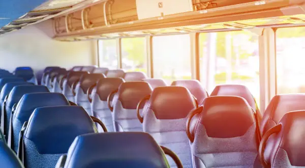 Puste siedzenia w autobusie lub pociągu, z oknami i światłem słonecznym.